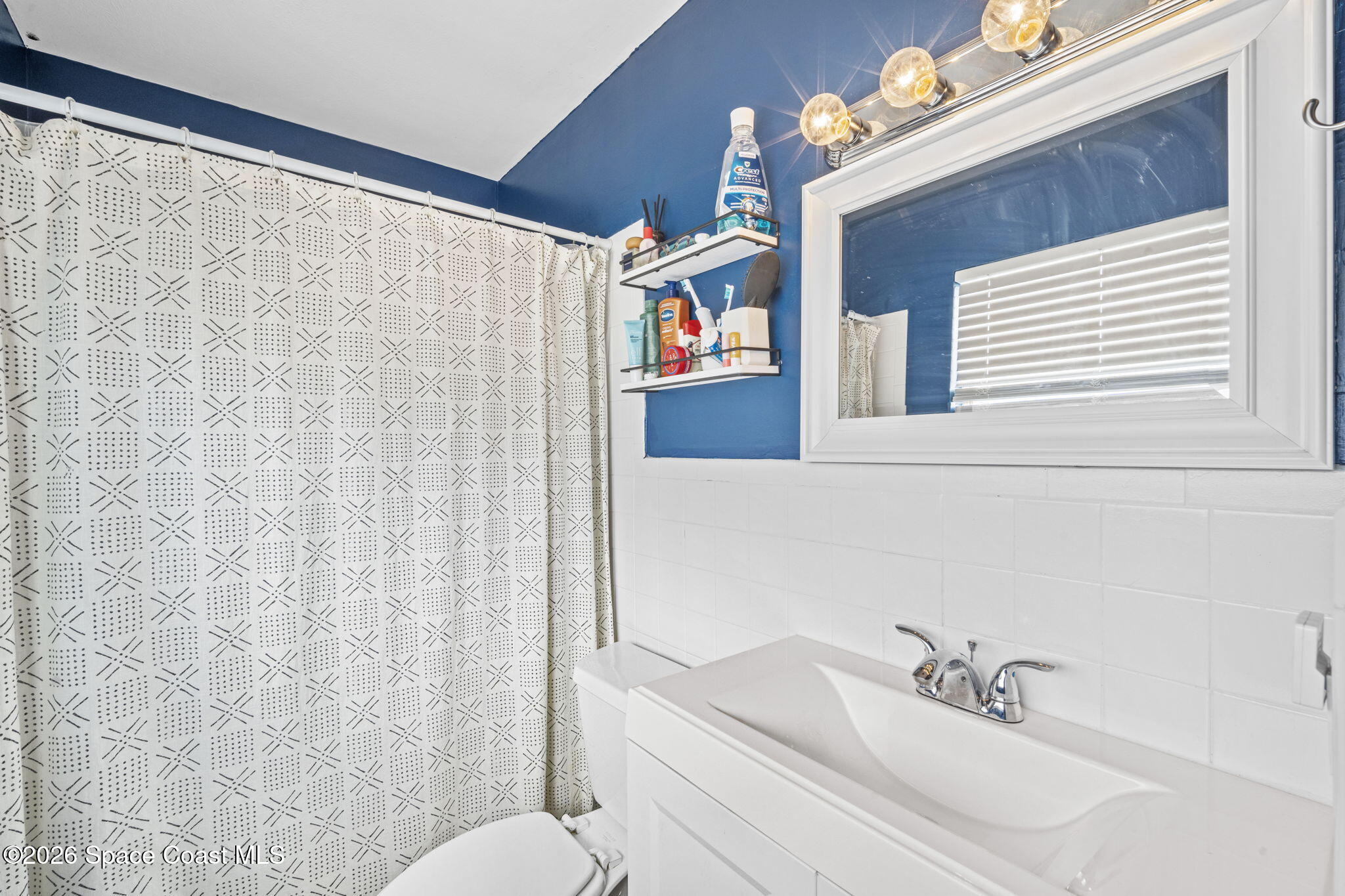 1088 Coronado Drive Rockledge, FL 32955 - Photo 17 of 23 a bathroom with a sink a toilet and shower curtain