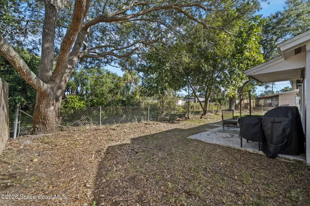 a view of a backyard with table and chairs under an umbrella