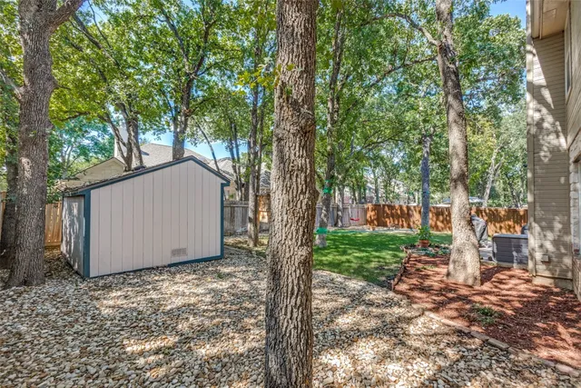 a view of backyard with large tree and wooden fence