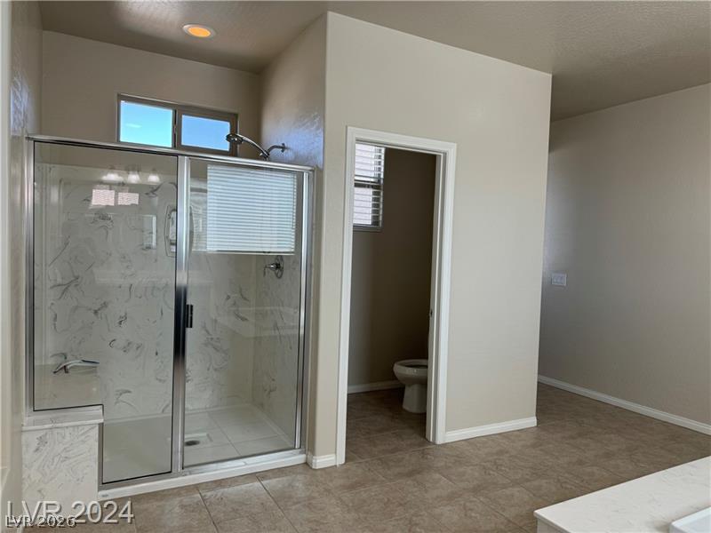 9056 Tony Ridge Avenue Las Vegas, NV 89148 - Photo 19 of 32 A well-lit primary bathroom features a spacious glass-enclosed shower and private commode area.