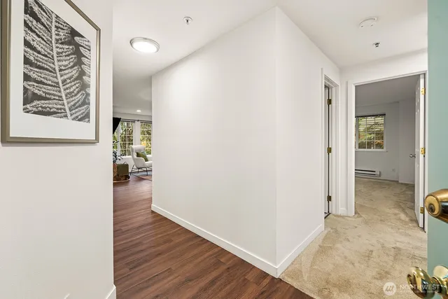 a view of a hallway with wooden floor and a bathroom
