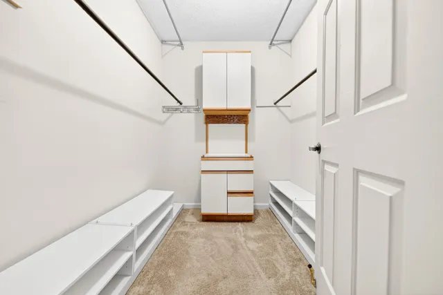 a view of an empty room with kitchen and window