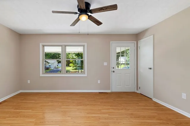 a view of an empty room with window and wooden floor
