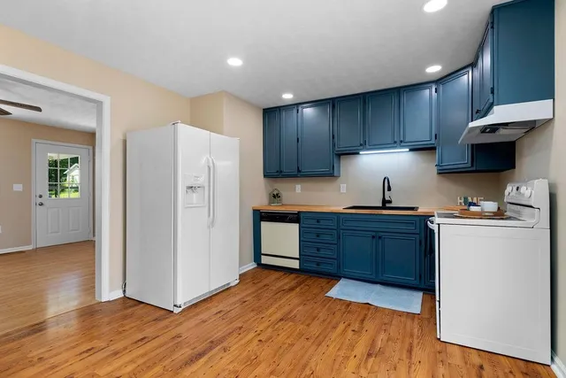 a kitchen with granite countertop wooden floors and white stainless steel appliances