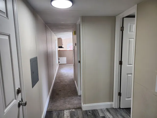 a view of a hallway with wooden floor and a bathroom