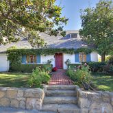a front view of a house with a yard and potted plants