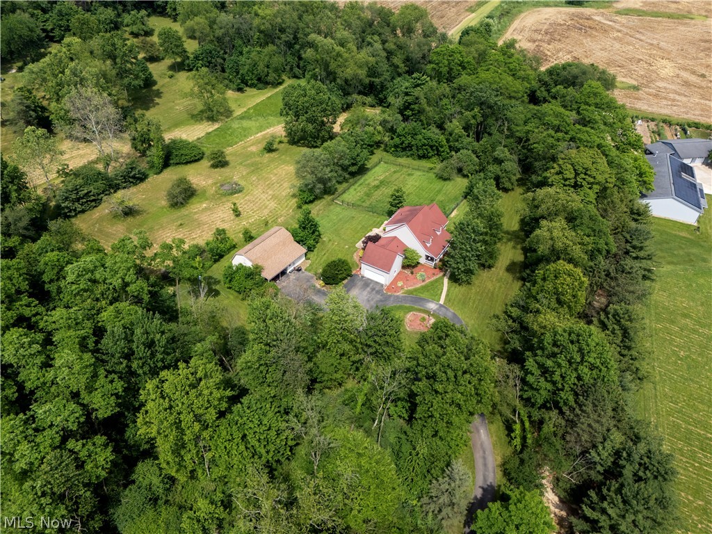 1043 North Honeytown Road Wooster, OH 44691 - Photo 41 of 46 Aerial perspective showcasing a light-colored exterior residence with a red roof, a detached auxiliary structure, and an extensive surrounding landscape