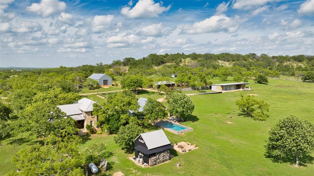 2969 County Lane Talpa, TX 76882 - Photo 3 of 40 Expansive property featuring multiple structures, including a stone-clad residence with a metal roof and a modern-style building