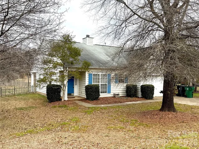 a view of a house with a yard and large tree