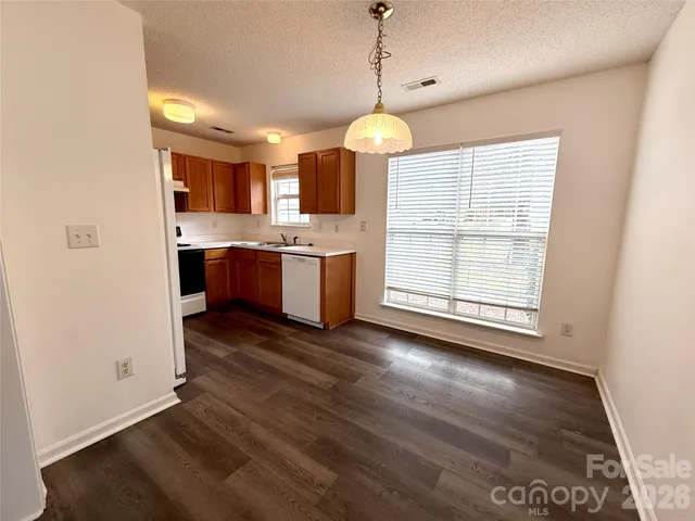 a view of kitchen with granite countertop stove top oven and refrigerator