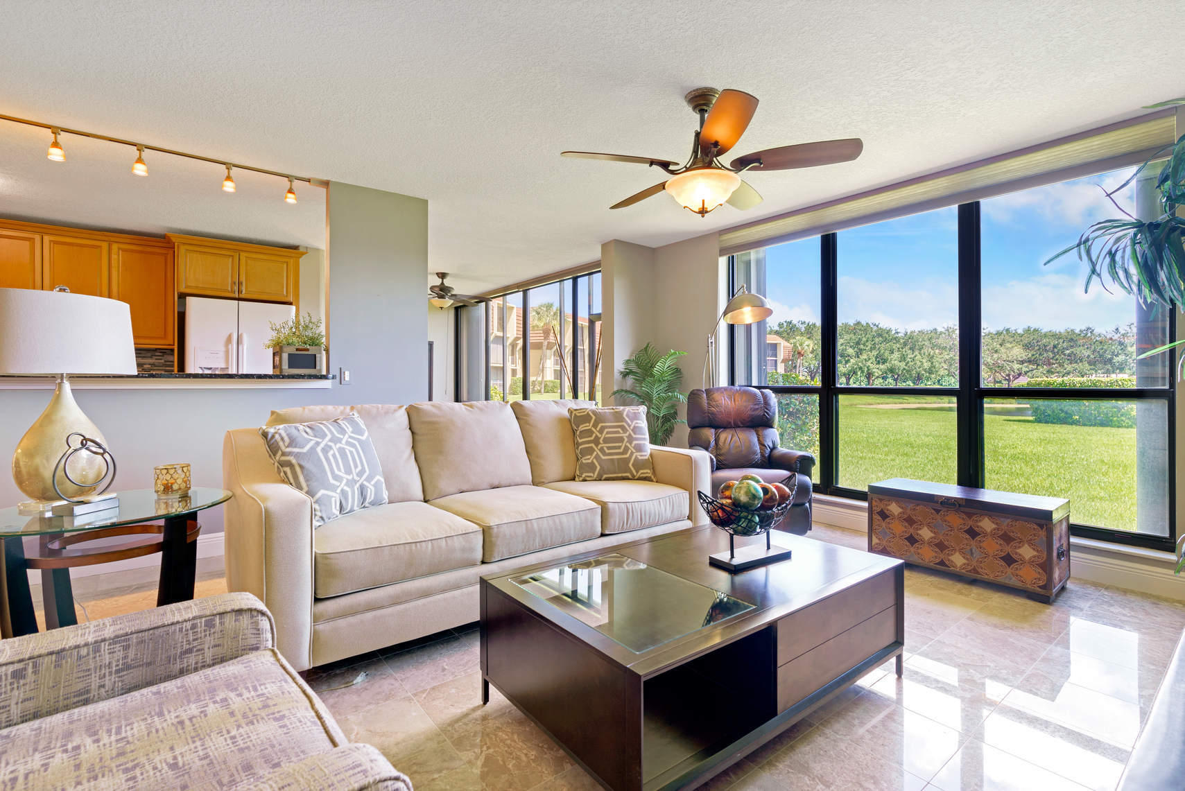 a living room with furniture ceiling fan and a large window