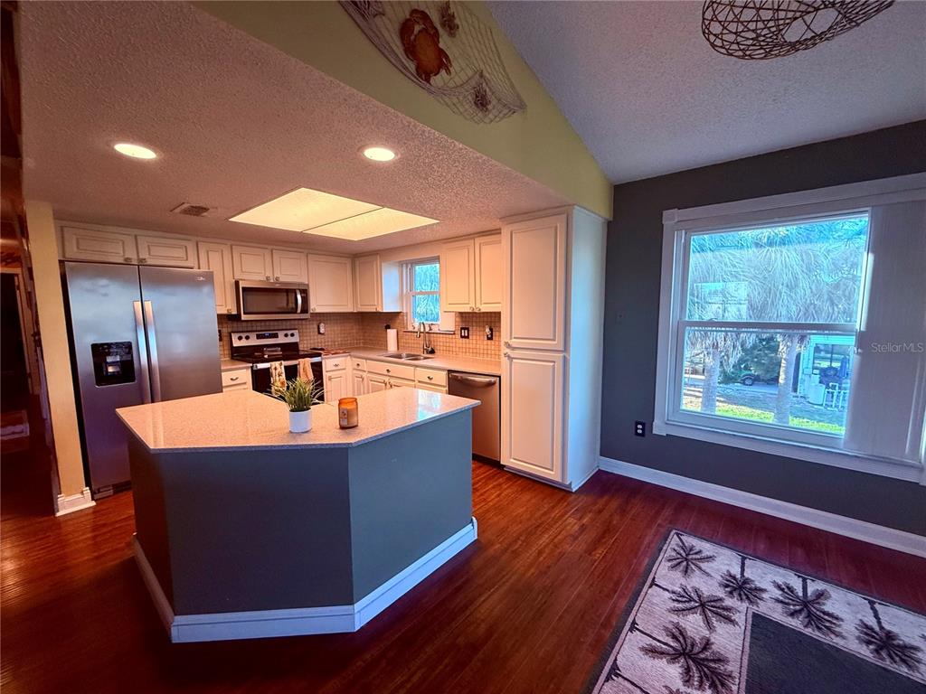 3338 Fernleaf Drive Hernando Beach, FL 34607 - Photo 14 of 69 a kitchen with stainless steel appliances granite countertop a refrigerator a sink dishwasher a stove and a dining table with wooden floor