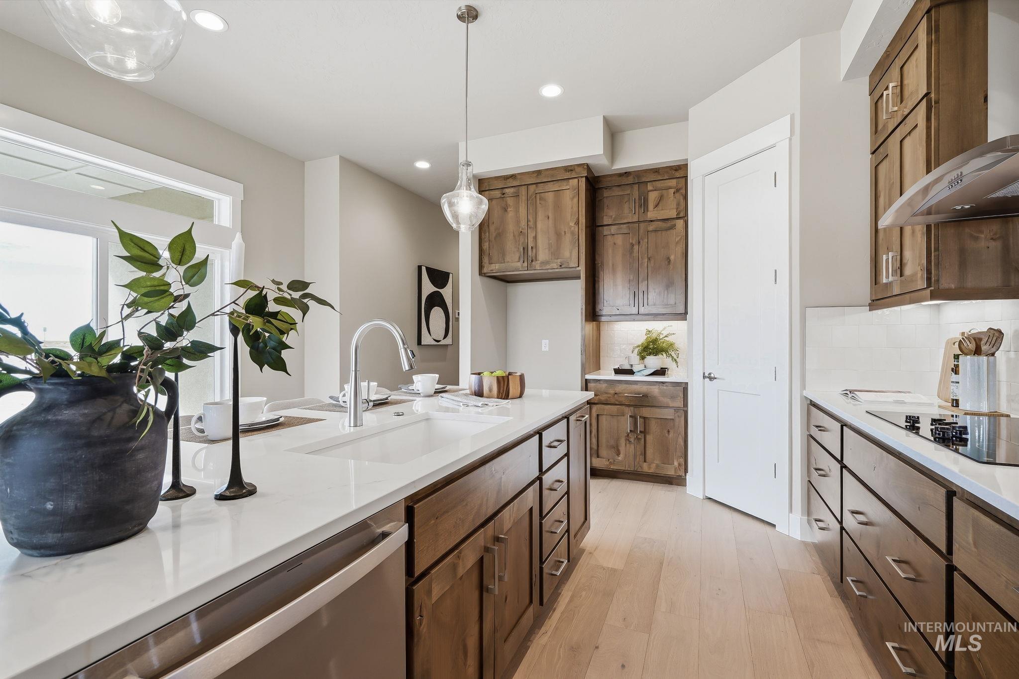 470 South Radiator Way Boise, ID 83716 - Photo 32 of 50 Bright kitchen showcasing an oversized island with an undermount sink, light wood-finish flooring, and white countertops