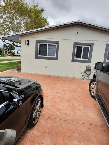 a view of a car garage with a car parked in a yard