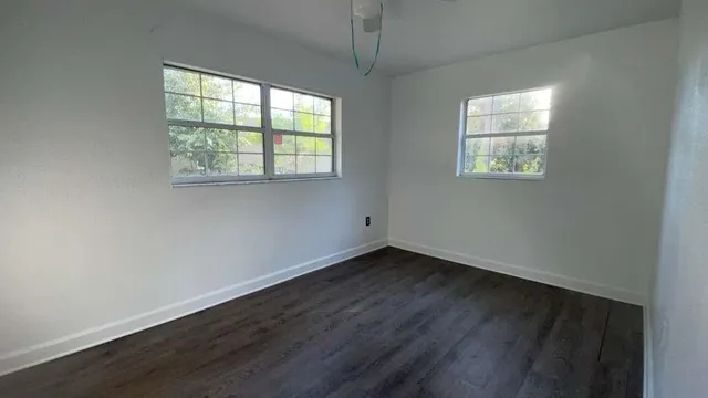 an empty room with wooden floor and windows