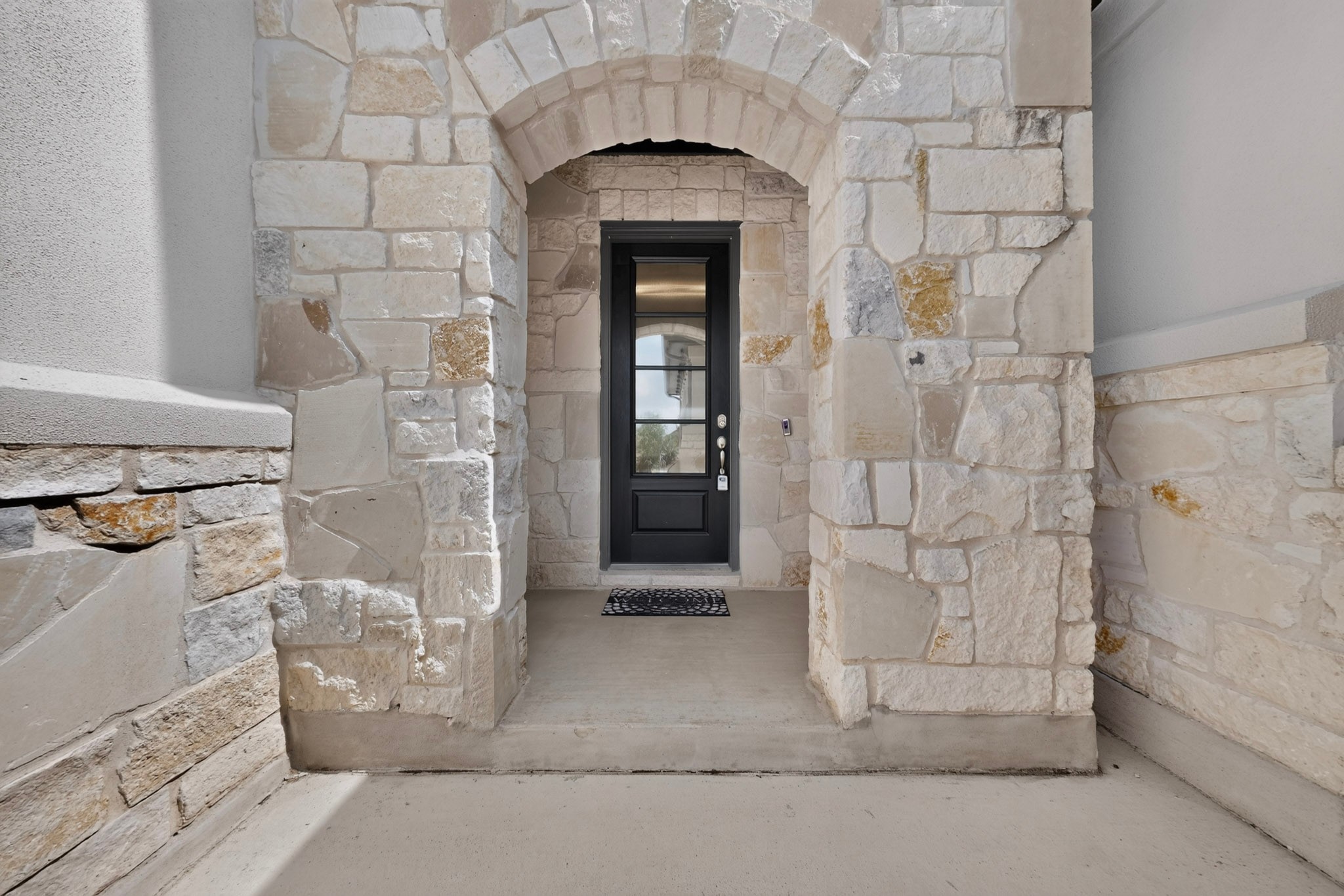 2433 La Mirada Street Leander, TX 78641 - Photo 4 of 25 A commanding stone archway frames the elegant dark entry door, creating a grand welcome.