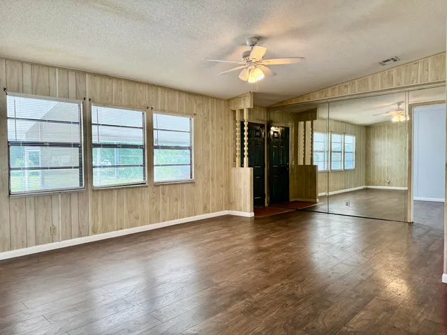 an empty room with wooden floor and windows