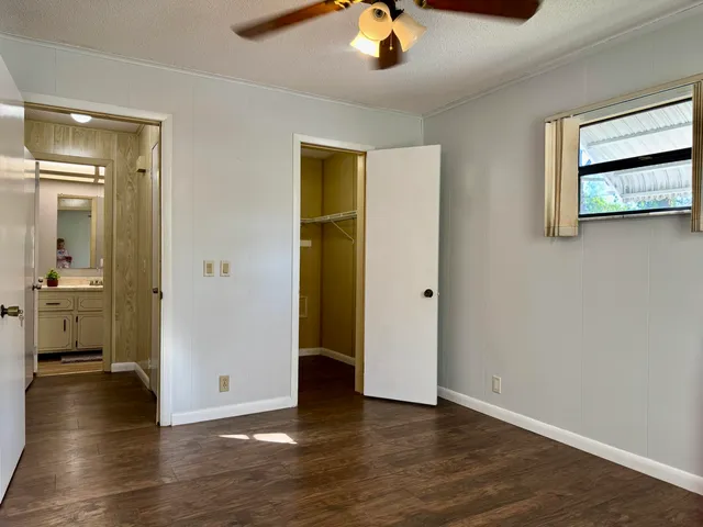 an empty room with wooden floor and a ceiling fan