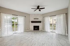 a view of a livingroom with a fireplace a ceiling fan and windows