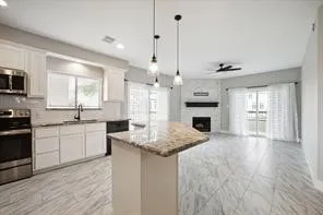 a kitchen with kitchen island granite countertop a sink cabinets and stainless steel appliances