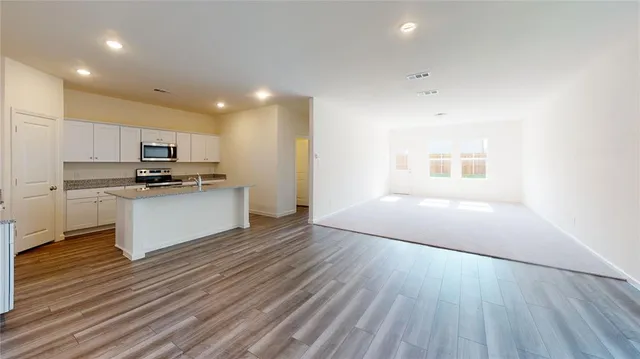 a kitchen with granite countertop a stove a sink and a refrigerator