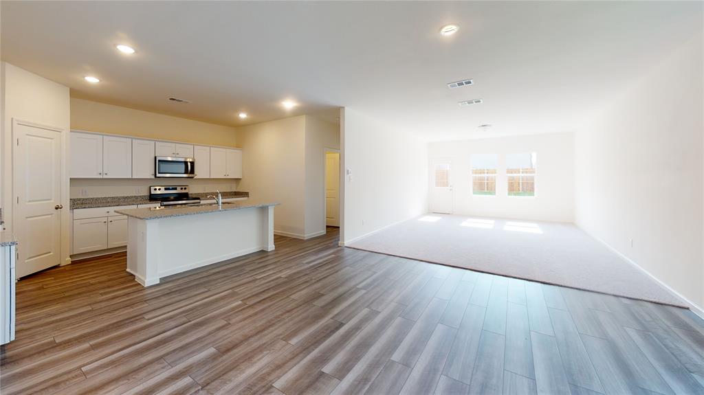 1706 Washington Street Princeton, TX 75407 - Photo 5 of 19 a kitchen with granite countertop a stove a sink and a refrigerator