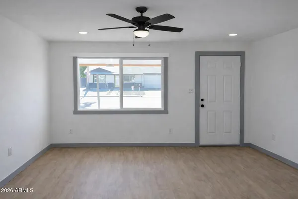 an empty room with a window and a fan