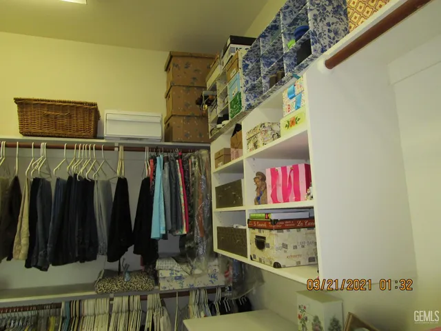 a view of walk in closet with clothes and shoes
