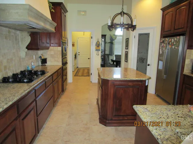 a kitchen with stainless steel appliances granite countertop a stove a refrigerator and a wooden cabinets