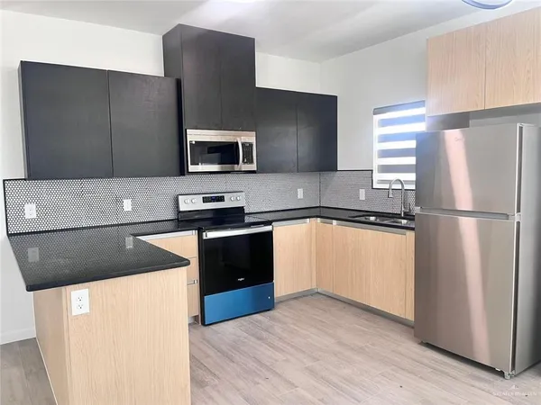 a kitchen with granite countertop a refrigerator and a stove top oven