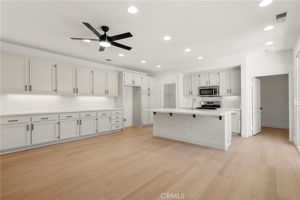 256 4 Seasons Boulevard Hemet, CA 92545 - Photo 6 of 31 a large white kitchen with stainless steel appliances kitchen island a white counter space a sink and cabinets