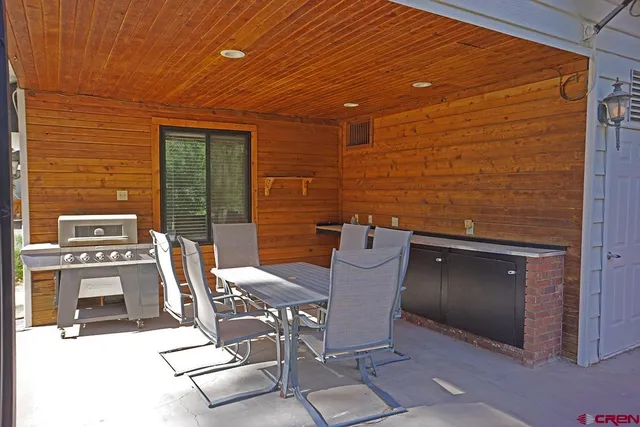 a view of a patio with table and chairs and barbeque