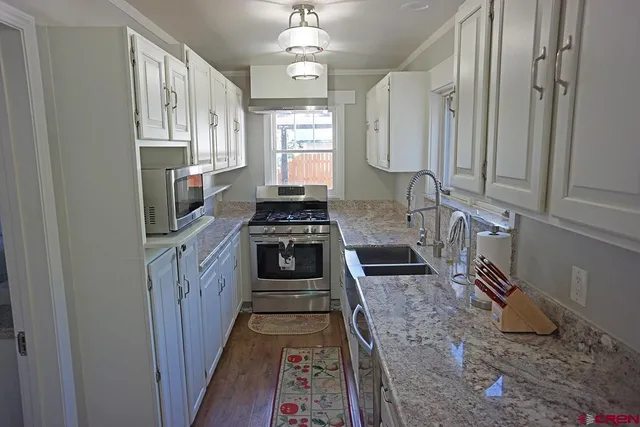 a kitchen with stainless steel appliances granite countertop a stove a sink and a refrigerator