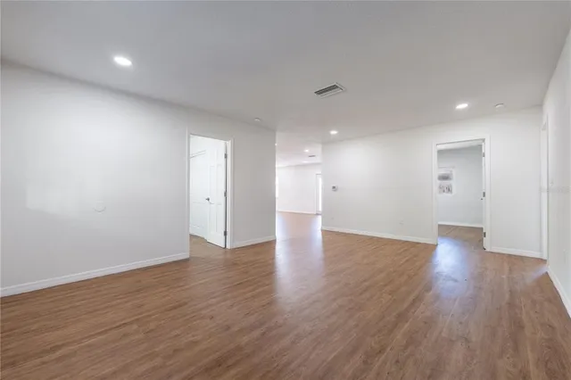 a view of an empty room with wooden floor and closet