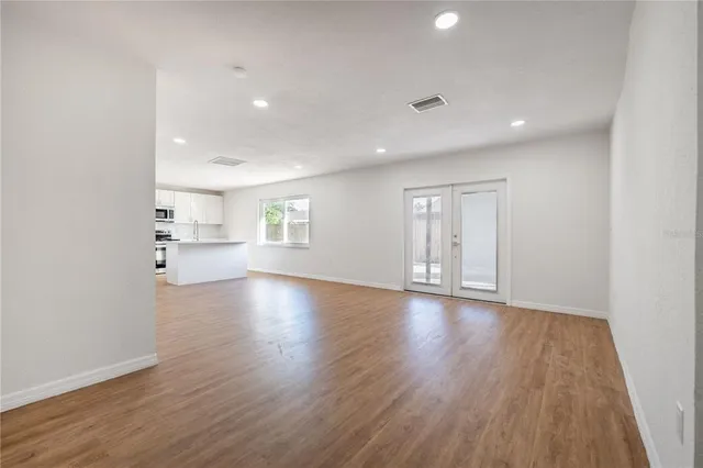 a view of empty room with wooden floor and kitchen