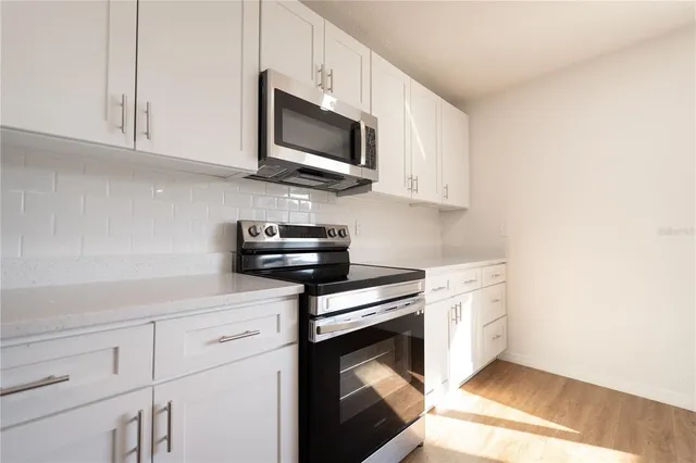 a kitchen with stainless steel appliances granite countertop white cabinets a stove top oven