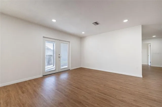 a view of an empty room with wooden floor and glass door