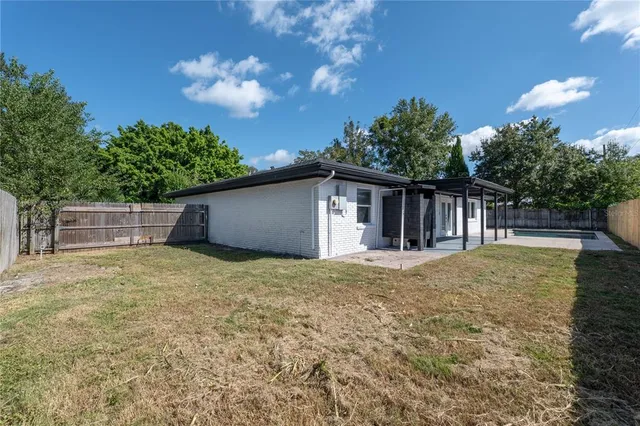 a backyard of a house with table and chairs plants and large trees