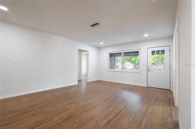 an empty room with wooden floor and windows