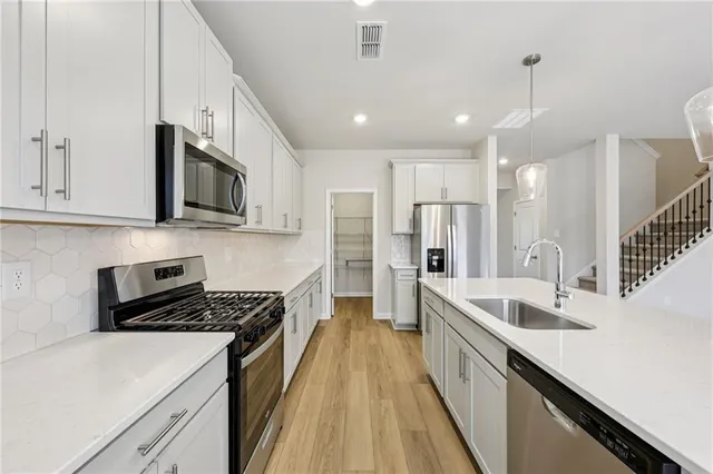 a kitchen with stainless steel appliances a sink a stove top oven a counter space and cabinets