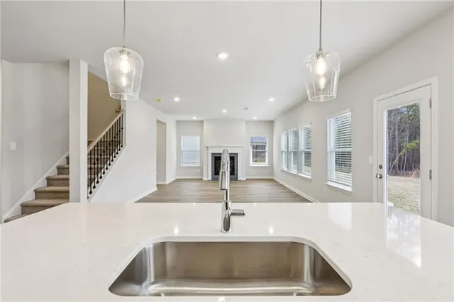 a kitchen with a sink a counter top space and living room view