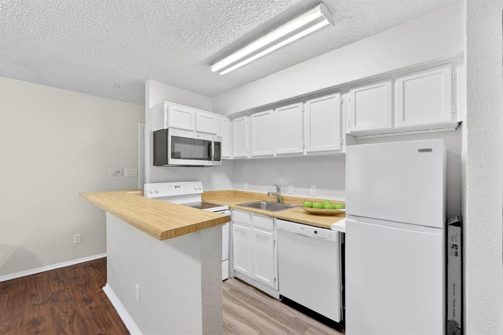9825 Walnut Street, Unit 306 Dallas, TX 75243 - Photo 4 of 23 a kitchen with a sink a stove a refrigerator and white cabinets