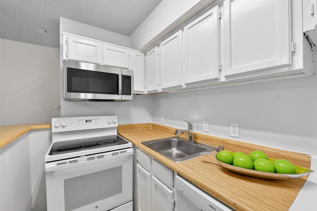 9825 Walnut Street, Unit 306 Dallas, TX 75243 - Photo 5 of 23 a kitchen with a stove a sink and a microwave