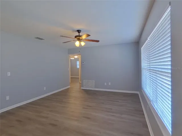 an empty room with wooden floor and fan