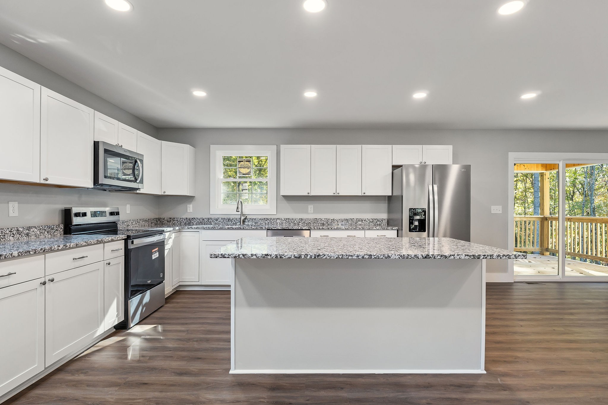1053 Benton Tidwell Road Hilham, TN 38568 - Photo 6 of 39 a large kitchen with granite countertop a stove a sink a refrigerator and white cabinets with wooden floor