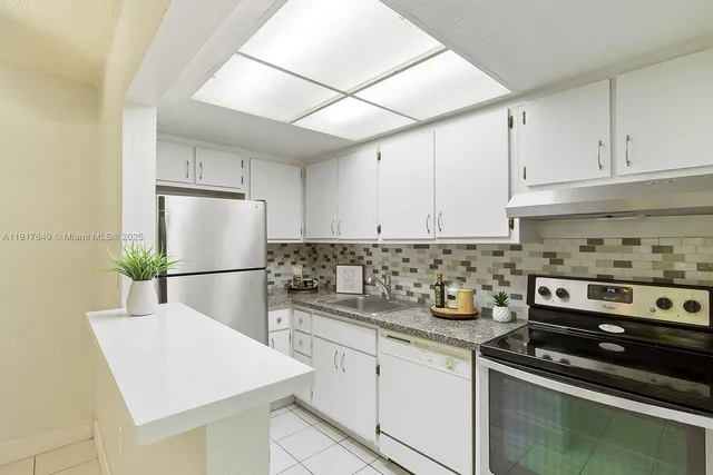 a kitchen with stainless steel appliances a sink a stove a refrigerator and cabinets