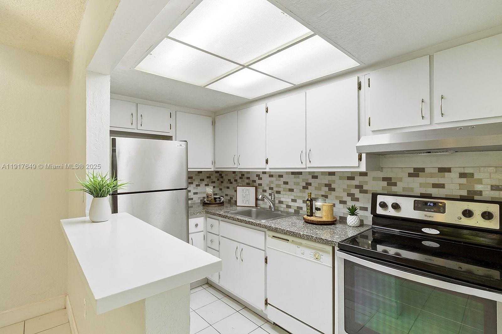 a kitchen with stainless steel appliances a sink a stove a refrigerator and cabinets