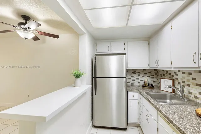 a kitchen with stainless steel appliances granite countertop a refrigerator a sink a stove a microwave oven with white cabinets