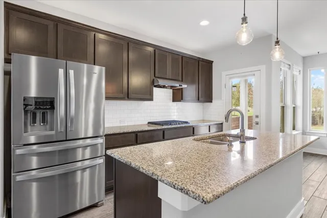 a kitchen with stainless steel appliances granite countertop a refrigerator and a sink
