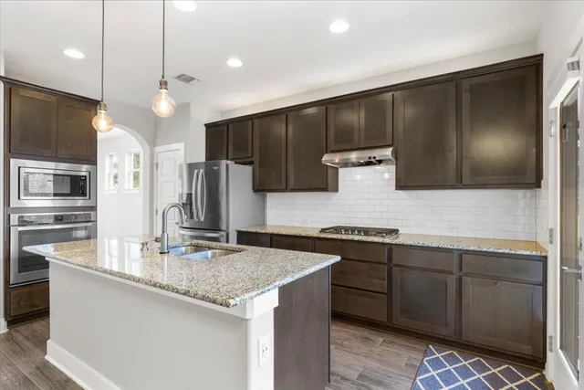 a kitchen with stainless steel appliances granite countertop a sink stove and refrigerator